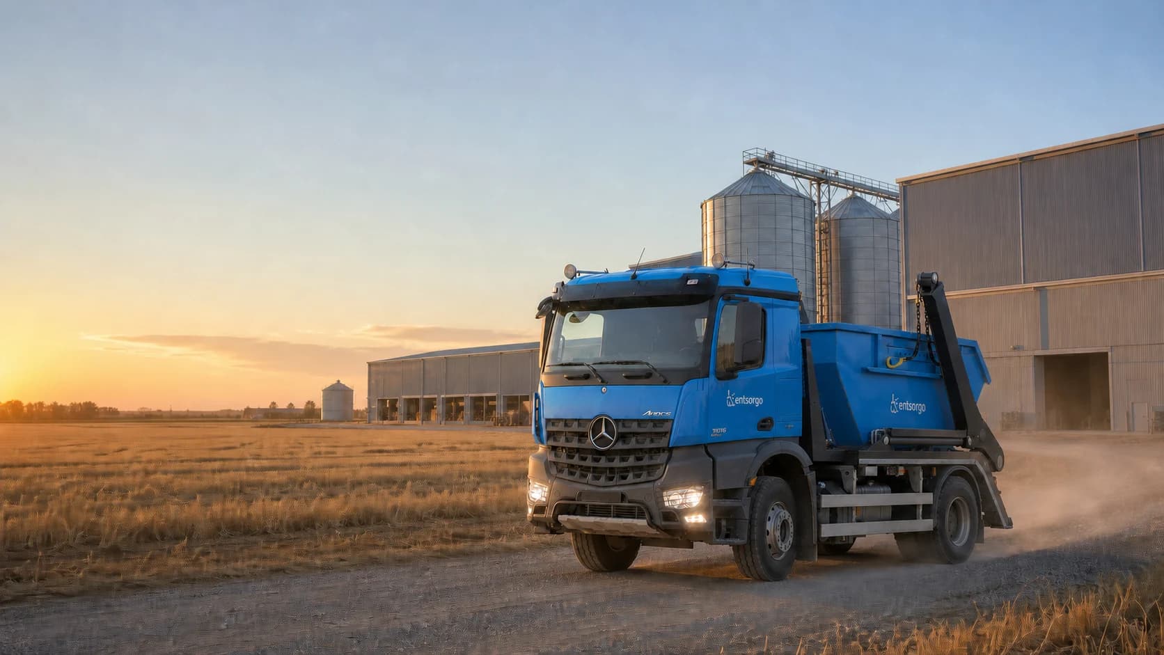 Entsorgo container truck outside grain stores and silos at sunrise